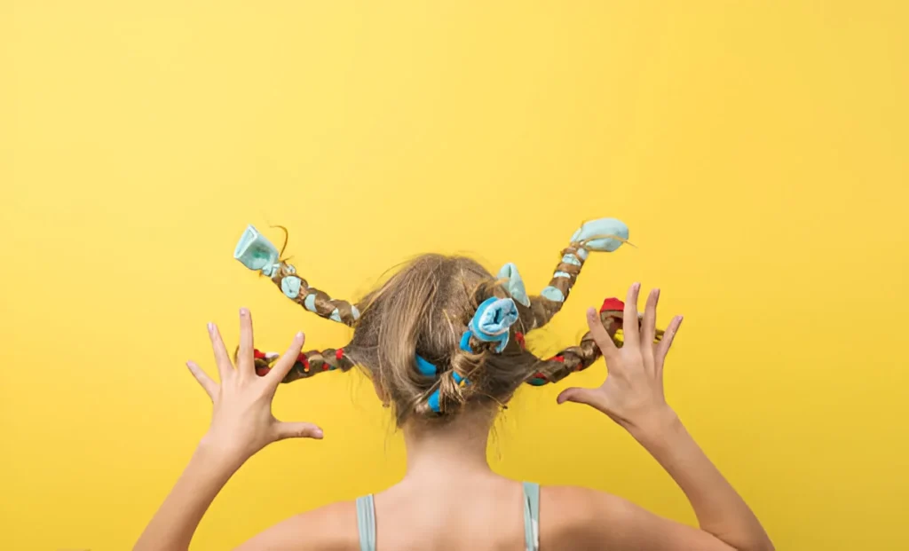 Girl with colorful, twisted braids showing off a fun and creative hairstyle for crazy hair day ideas against a bright yellow background.
