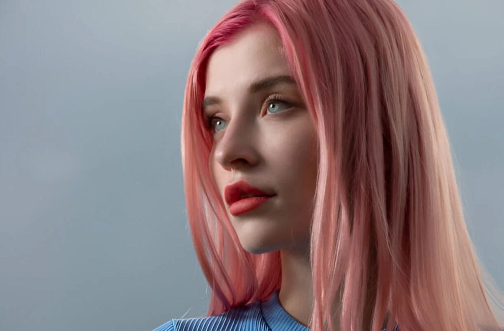 A person with long, straight rose gold hair wearing a blue top against a soft, blurred gray background.