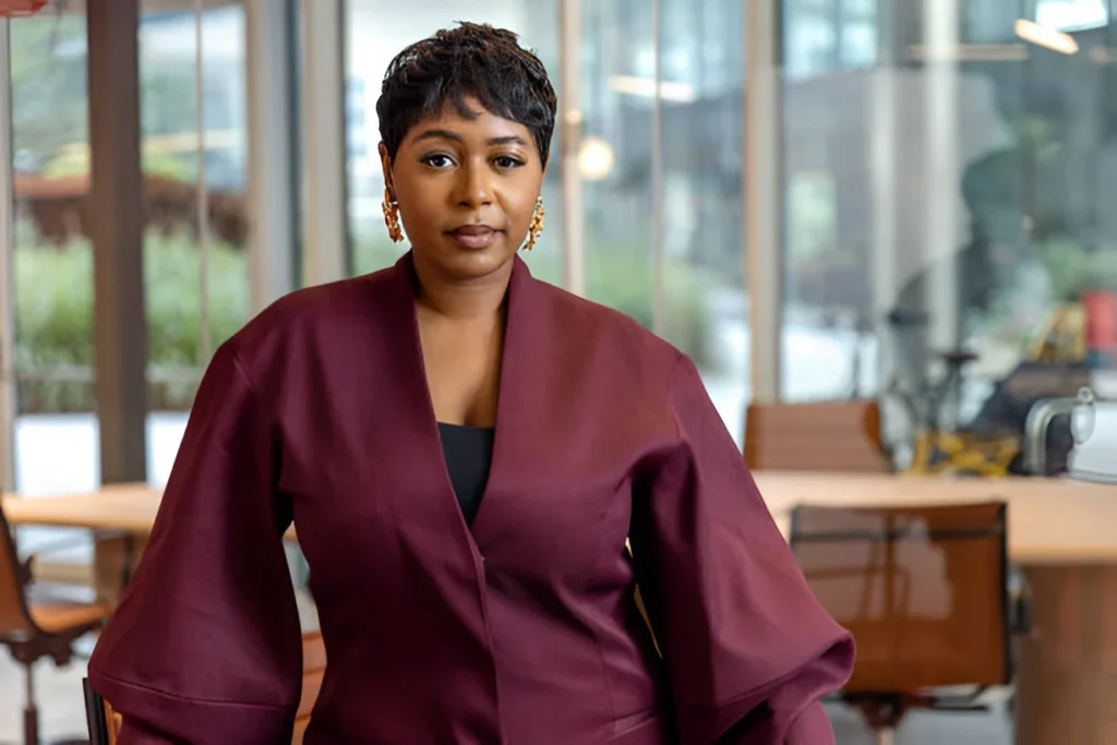 Elevate your style with a professional look featuring short, curly hair styled with a chic deep burgundy jacket and statement gold earrings.
